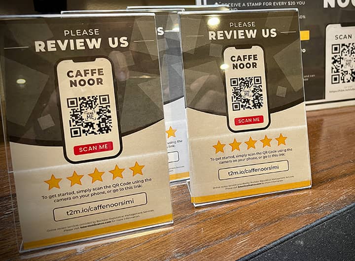 Table top stands with review request QR codes for customers to scan with their phone and craft an online review